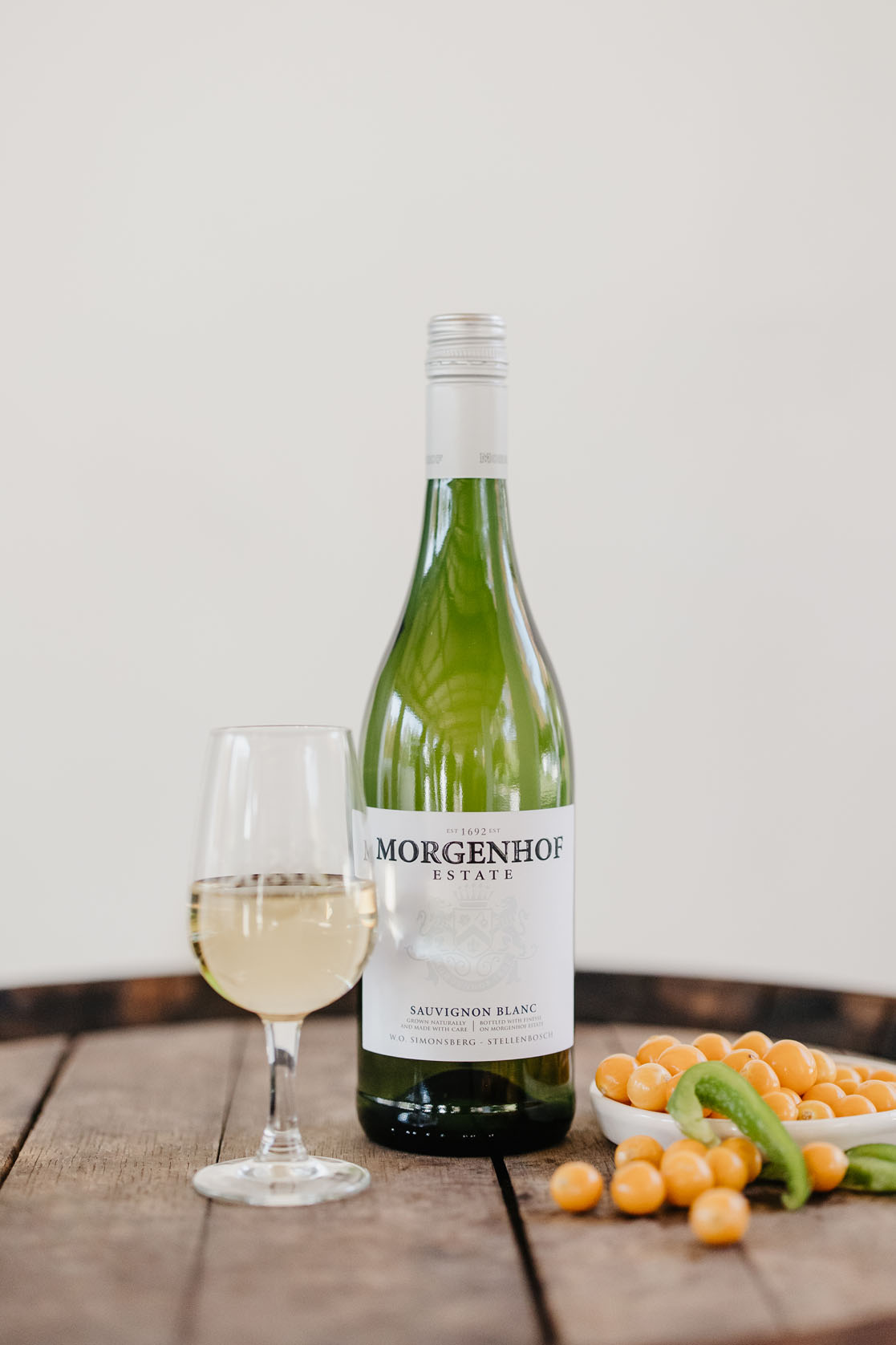 Morgenhof Estate Sauvignon Blanc bottle and a glass of white wine with cape gooseberries